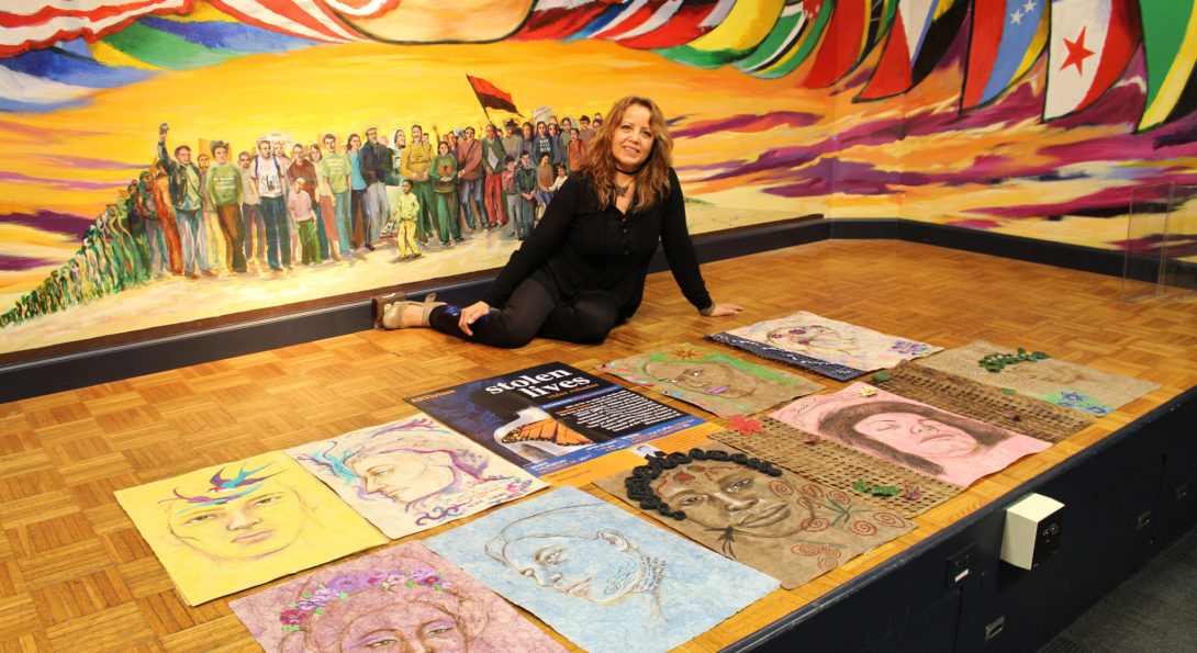Esperanza Gama sitting by the 10 pieces of collaborative art