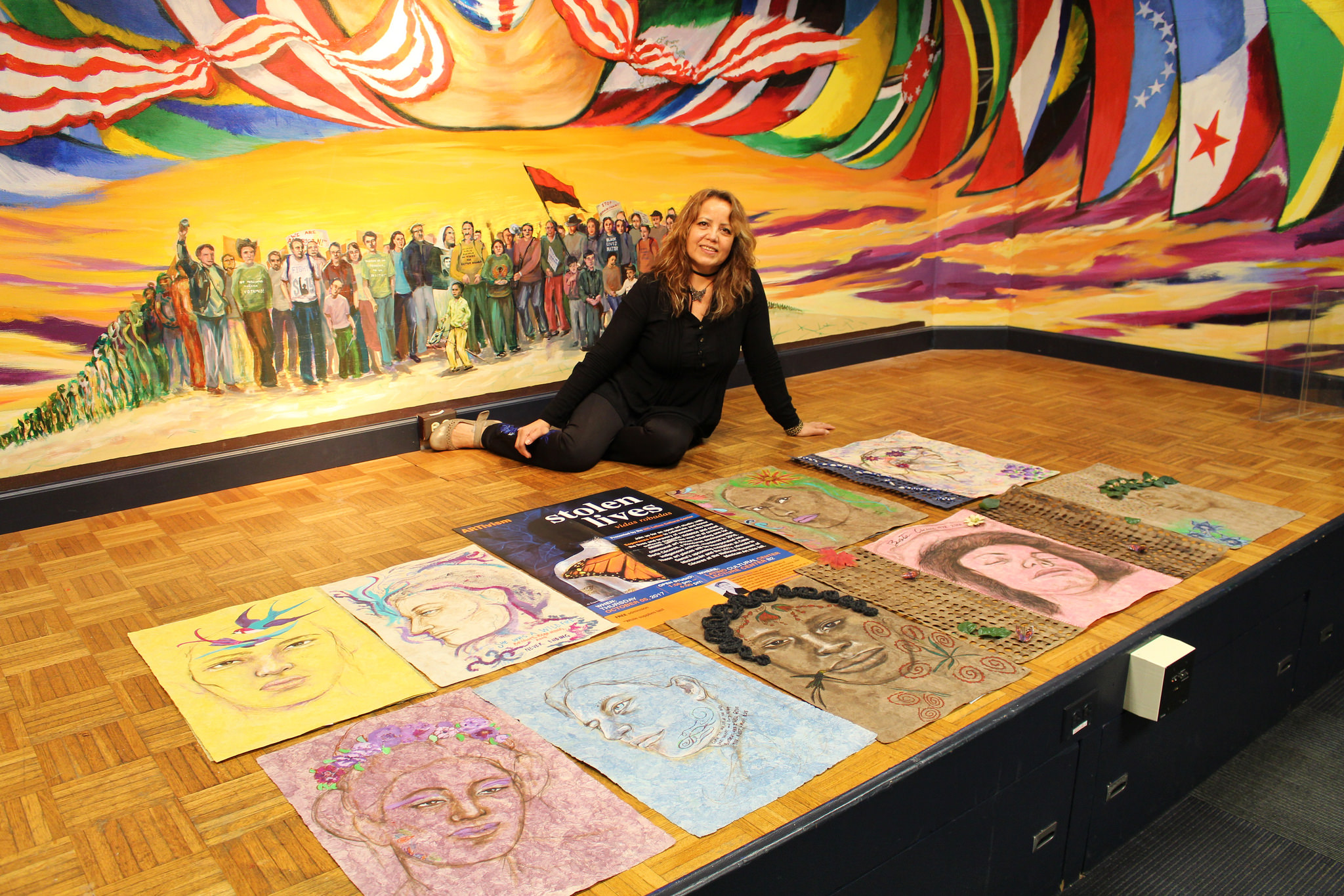 Esperanza Gama sitting by the 10 pieces of collaborative art
                  