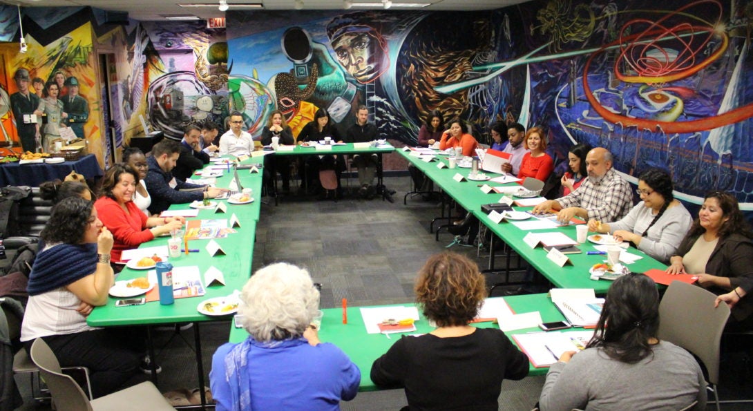 The LCC Ambassadors hosting a meeting in the LCC gallery. They are on green tables with notes and food talking amongst themselves.