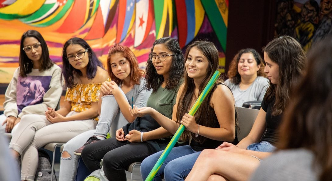 Students from L@s Ganas during a storytelling event. Woman is holding the talking stick while classmates listen.