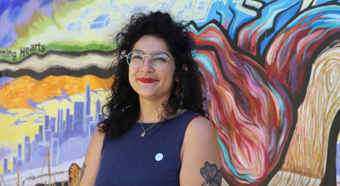 Photo of Sarita outside of the LCC in front of the mural