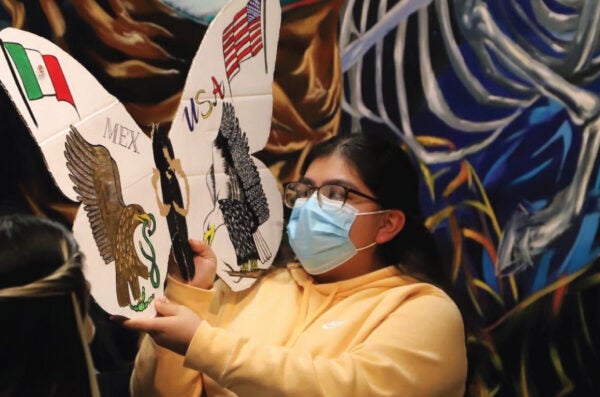 Student holding up a decorated cutout of a monarch butterfly